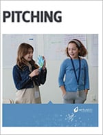 Two women in an office setting, one holding papers and the other presenting a free entrepreneurship curriculum, with a title "pitching" and a company logo below.