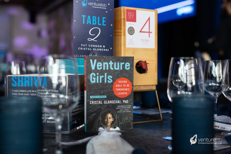 Table setting with a sign for Table 2, a wooden dispenser, and books titled 