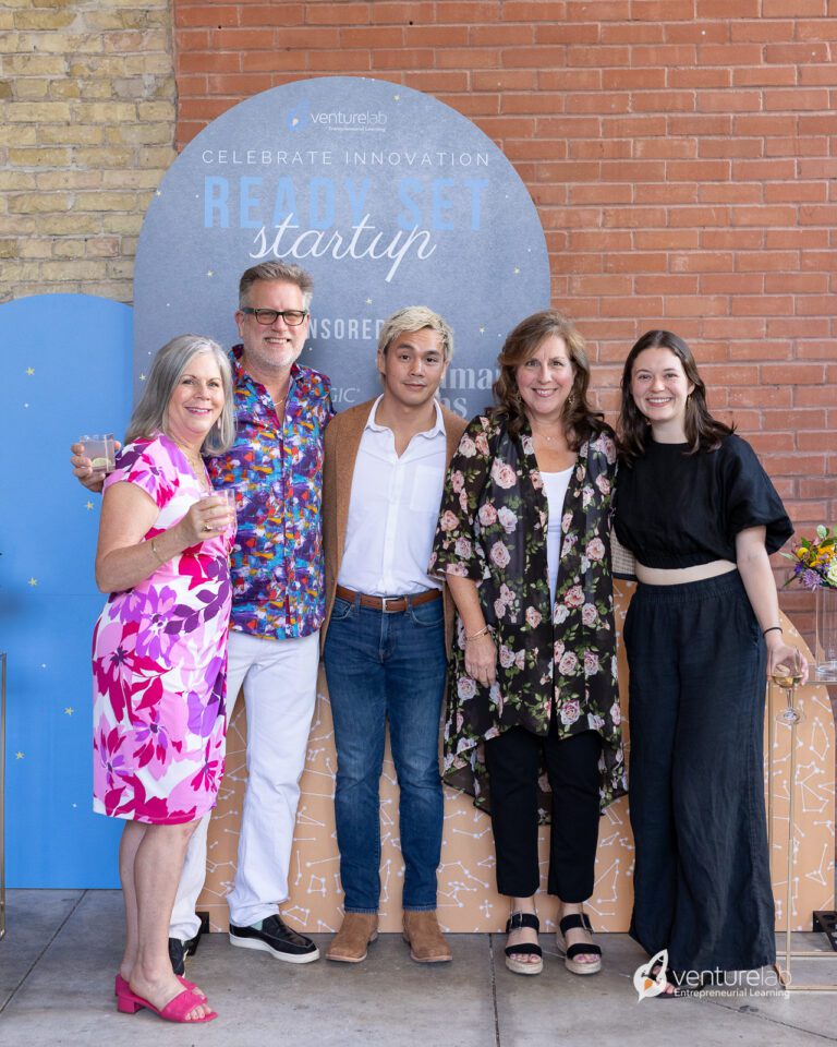 A group of five people stands in front of a backdrop that reads 