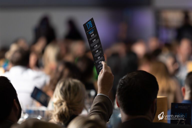 A person holds up a bidding paddle with 