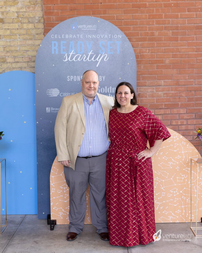 A man and woman stand together in front of a 
