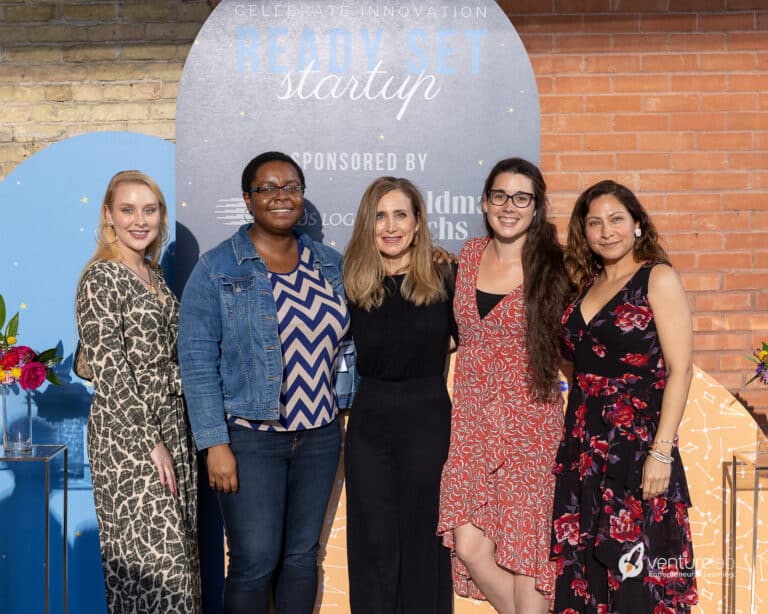 Five women standing together at an event with a 