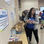 In the Garcia Center, people are organizing snacks into boxes on a table in a room adorned with posters, preparing for the near peer mentoring program's spring break camp.