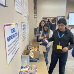 People sorting snacks into boxes on a table at the Garcia Center, surrounded by posters about idea generation, create an inspiring scene. This activity is part of the Garcia Center Spring Break Camp Youth Entrepreneurship program, fostering learning through near peer mentoring.