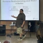 At the Garcia Center Spring Break Camp, a person presents a slide titled "Reverse Brainstorming and Make it Better," highlighting a list of problems and innovative solutions. This engaging session is part of the Youth Entrepreneurship program, designed to inspire young minds.