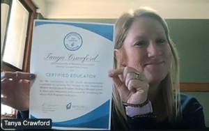 Tanya Crawford proudly holds a "Certified Educator" certificate during a video call. As her name tag suggests, she is recognized as a VentureLab Certified Educator, imparting entrepreneurial learning skills straight from Nebraska.