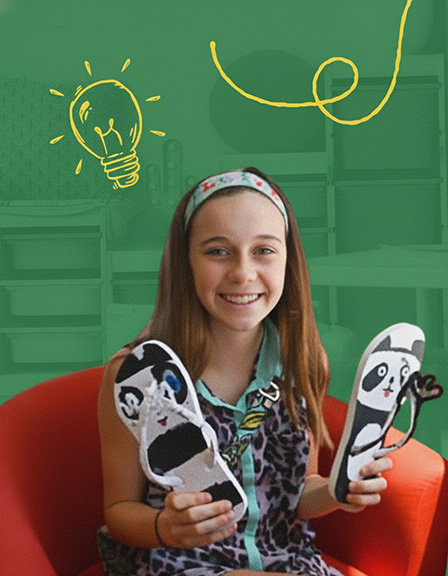 oung girl holds up her flip flop designed displaying her entrepreneurial skills.